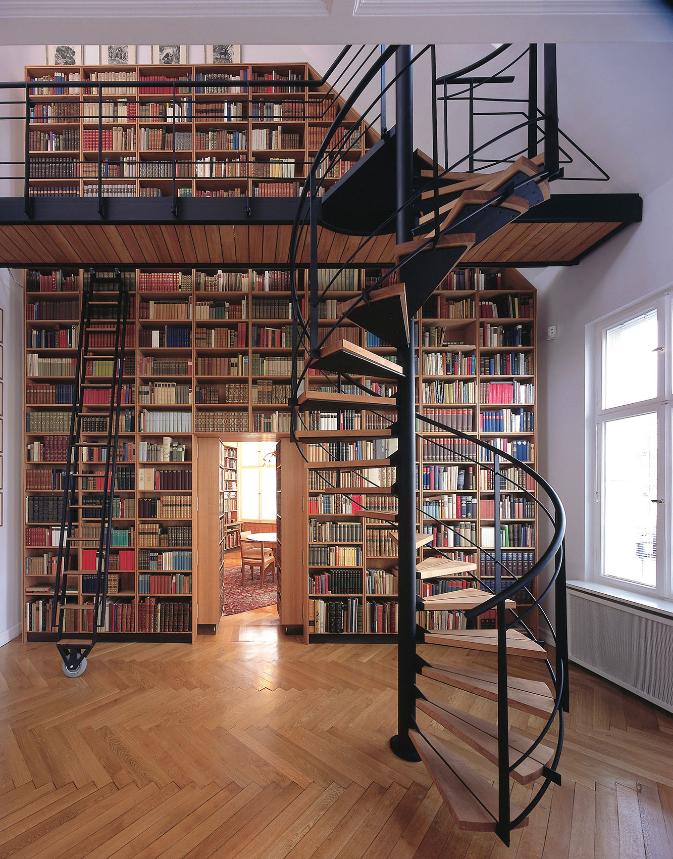 Ein hohe Bibliothek über zwei Stockwerke, mit einer Wendeltreppe
